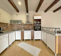 A kitchen in a family house with a wooden decor floor, light furniture, and brick cladding.