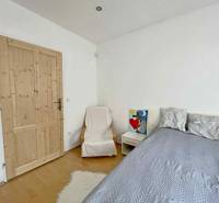 Bedroom in a family house with a wood-decor floor, decorations, and a bed.