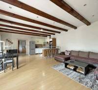 Living room of a family house with a wood-patterned floor, a large sofa, and a dining table.