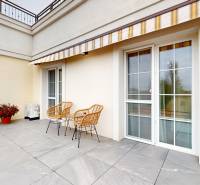 A terrace with tiles, wicker chairs, and an awning in a studio apartment in Komárno.