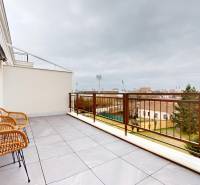 Spacious balcony in Komárno at a 1-room apartment with rattan chairs and a view of the city.
