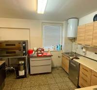 Kitchen gastro spaces with an oven, cabinets, and a sink on a stone floor.