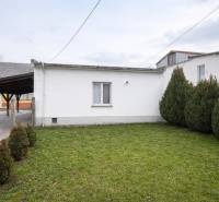 A space in Pribete with a lawn, trees, and a simple white structure for gastro use.