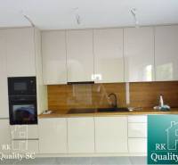 A kitchen with glossy white cabinets and a countertop with a wood decor.