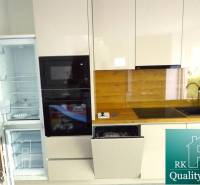A kitchen with built-in appliances and a wooden decor floor in a 3-room apartment.