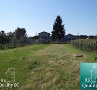A plot for residential use on Vrbová Street in Jelka, surrounded by greenery and fencing.