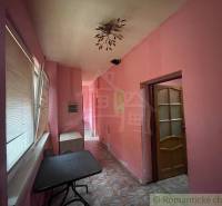 Interior of a family house with pink walls, tiled floor, and a table.