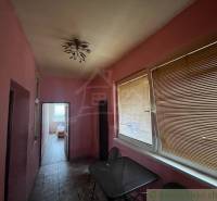 A hallway in a family house with pink walls, blinds, and a ceiling light.