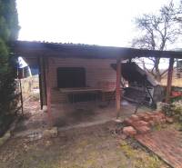 A shelter from gardens in Nové Mesto nad Váhom with wooden pillars and stored bricks.