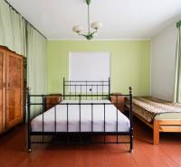 Bedroom in a family house with a metal bed, wooden wardrobe, and green curtains.