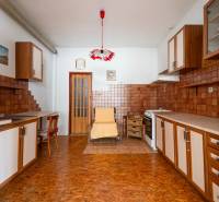 A kitchen in a family house with wooden cabinets, tiles, and a floor with a wooden decor.