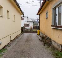 A narrow courtyard between family houses in Bobot on Bobot Street with a gate and a trash can.