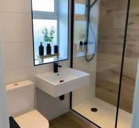 Bathroom in a 3-room apartment with a glass shower enclosure and a floor with a wooden decor.