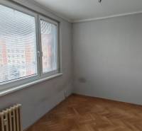 A room with a wooden decor floor and a large window in a 3-room apartment.