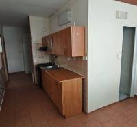 A narrow kitchen in a 3-room apartment with tiled flooring and wooden cabinets.