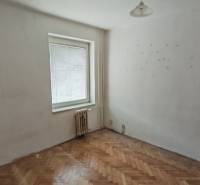 A room in a 3-room apartment with a wooden decor floor, white walls, a window, a radiator.