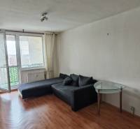 Living room in a three-room apartment with a wooden decor floor and a view through a large window.