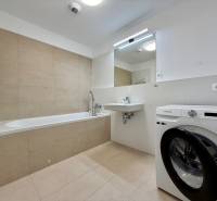 Bathroom in a 3-room apartment with a bathtub, washing machine, and sink, bright tiles.