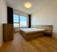 A bedroom with wood-patterned flooring and a view in a 3-room apartment.