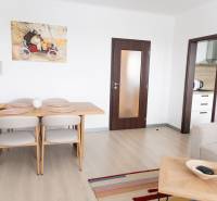 Dining room in a 4-room apartment with a wooden decor floor and an artistic painting on the wall.