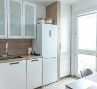 Spacious kitchen in a 4-room apartment with white cabinets and a large window.