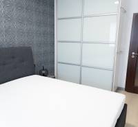 Bedroom in a 4-room apartment with an upholstered bed, wallpaper, and a built-in wardrobe.