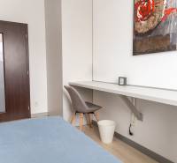 A room in a 4-room apartment with a wooden decor floor, a table, and a chair.