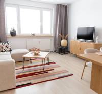 Living room in a 4-room apartment with a wooden decor floor, a sofa, and a television.
