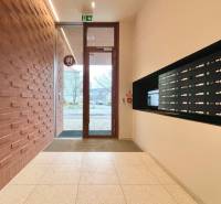 Entrance to the apartment building with mailboxes and a brick wall on Košická in Bratislava.