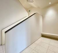 A staircase with white walls, a railing, and a stone floor in a residential building.
