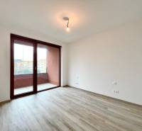A room in a 2-room apartment with a wooden decor floor and a balcony.