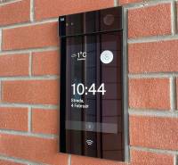 Digital doorbell on a brick wall, showing the time and temperature in Bratislava.