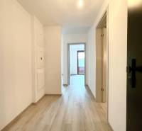 A hallway in a 2-room apartment with a wooden decor floor and white walls.