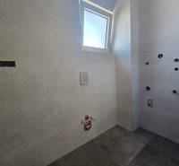 A bathroom in a family house with ceramic tiles and flooring, ready for final installation.