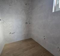 A bathroom in a family house with a wooden decor floor and leaf-patterned tiles.