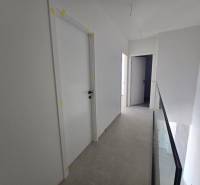 A hallway in a family house with white doors and glass railing.
