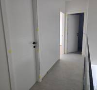 Hallway in a family house with multiple doors and light-colored walls.