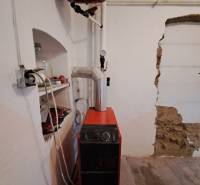 Boiler room in a family house with a boiler and an expansion tank, floor with a wooden decor.