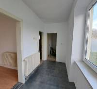A hallway of a family house with white walls and large windows, floors with various designs.