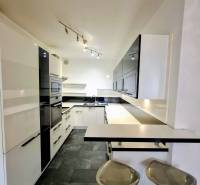 A kitchen in a 3-room apartment with bar stools, black and white cabinets.
