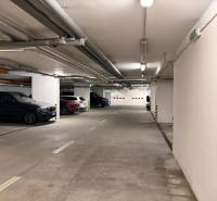 Underground garage with parking spaces, concrete walls, and lighting.