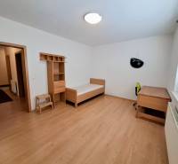 A room in a 3-room apartment with a bed, a table, and a floor with a wooden decor.