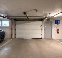 Garage parking with a gate, car, and fire extinguisher, part of a 3-room apartment.
