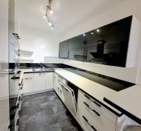 A modern kitchen in a 3-room apartment with black and white cabinets and a glossy floor.