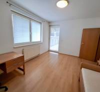 A room in a 3-room apartment with a wooden decor floor, a desk, and a wardrobe.