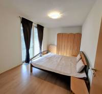 Bedroom in a 3-room apartment with a bed, wardrobe, and wooden decor flooring.