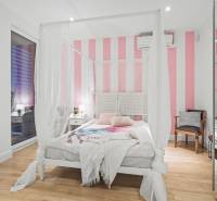 Bedroom with a white-pink wall, canopy, and wooden decor flooring in a family house.