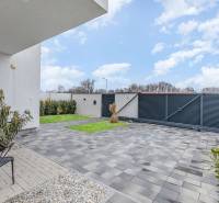 Courtyard of a family house in Dunajský Klátov, paving, greenery, modern fence, and parked car.