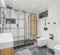 A bathroom in a family house with a glass shower enclosure, double sink, and white tiles.