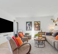 Living room in a family house with comfortable seating, colorful pillows, and a large television.